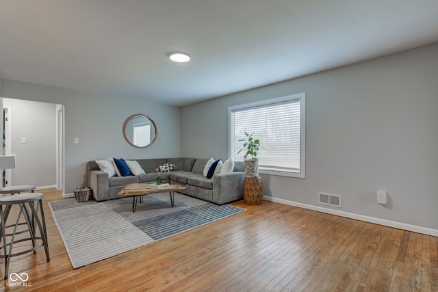 living room featuring visible vents, light wood-style flooring, and baseboards