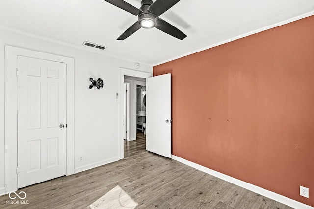 unfurnished bedroom with visible vents, crown molding, ceiling fan, baseboards, and wood finished floors