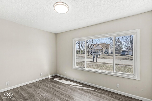 empty room featuring wood finished floors, baseboards, and a textured ceiling