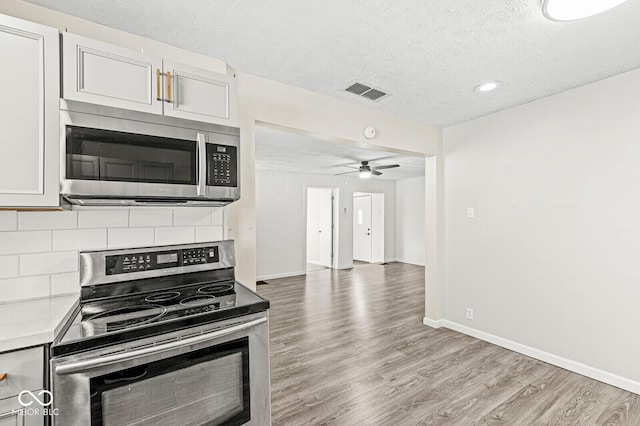 kitchen featuring visible vents, backsplash, light countertops, light wood-type flooring, and appliances with stainless steel finishes