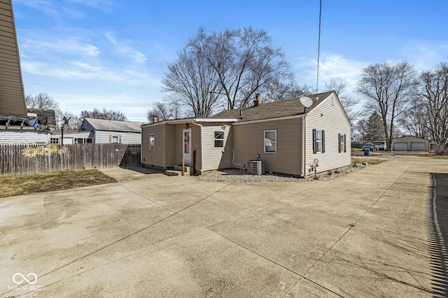 back of house featuring central AC unit, a chimney, an outdoor structure, and fence