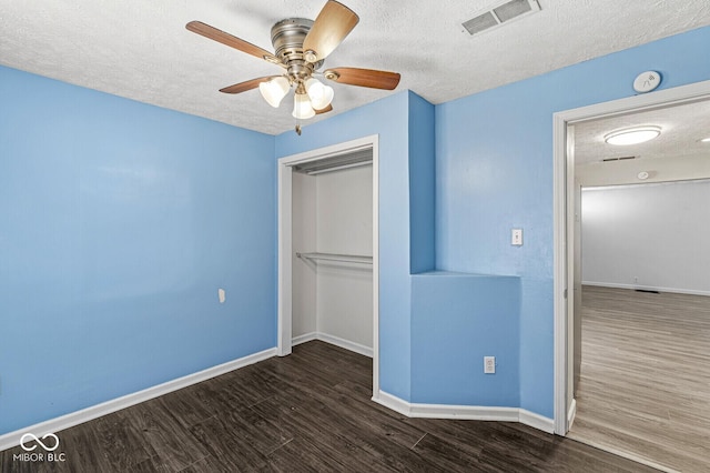 unfurnished bedroom featuring visible vents, baseboards, wood finished floors, a closet, and a textured ceiling