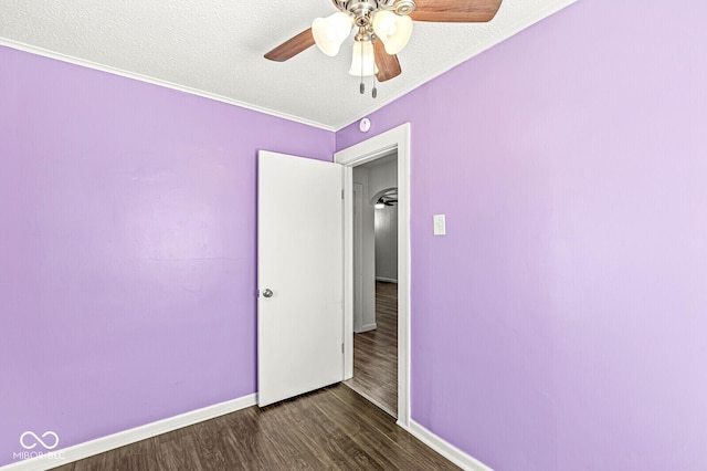 spare room with wood finished floors, baseboards, ceiling fan, a textured ceiling, and crown molding