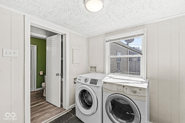 laundry area with a textured ceiling, laundry area, wood walls, and washer and clothes dryer