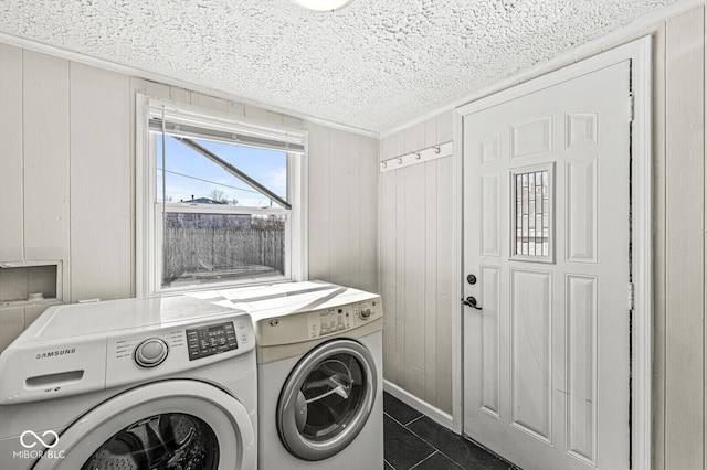 laundry room with a textured ceiling, washing machine and dryer, wooden walls, crown molding, and laundry area