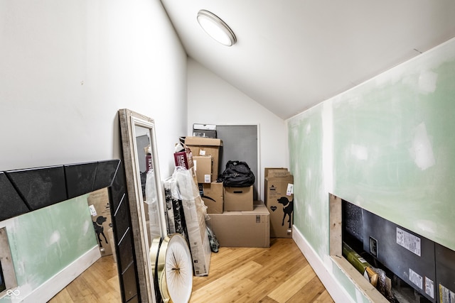 interior space featuring baseboards, vaulted ceiling, and wood finished floors