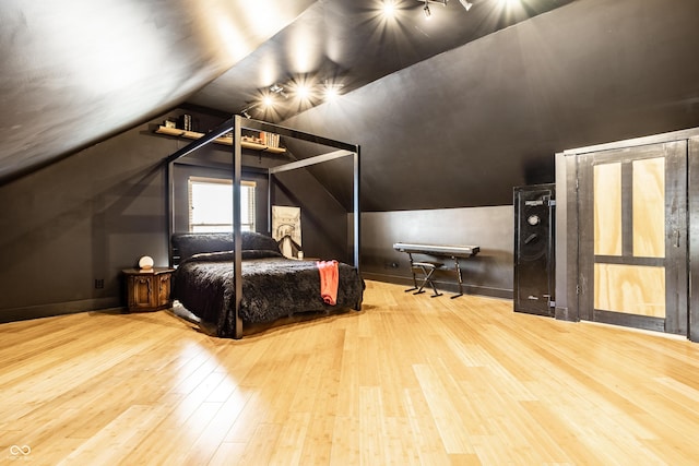 bedroom featuring lofted ceiling, baseboards, and wood finished floors