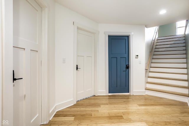 entryway with light wood-type flooring, stairway, baseboards, and recessed lighting