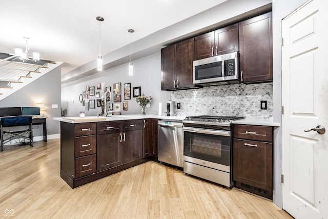 kitchen with light wood finished floors, tasteful backsplash, open floor plan, a peninsula, and stainless steel appliances