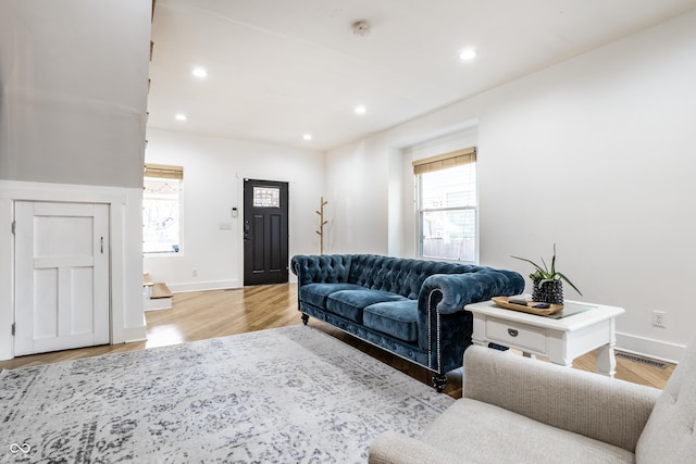 living area with light wood-style flooring, visible vents, baseboards, and recessed lighting