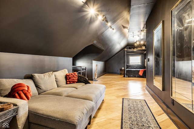 cinema room featuring lofted ceiling, wood finished floors, and track lighting