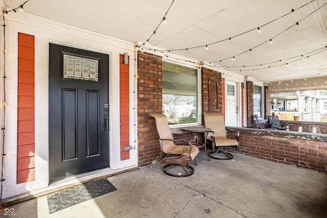 entrance to property featuring covered porch and brick siding