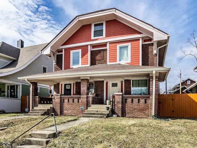 view of front of home with covered porch, brick siding, and a front lawn