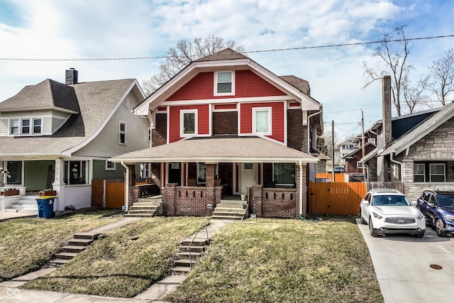 view of front facade featuring a porch, a front yard, fence, and brick siding