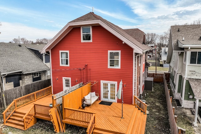 back of house featuring a wooden deck, fence, a shingled roof, and french doors