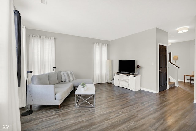 living area with dark wood finished floors, stairway, and baseboards