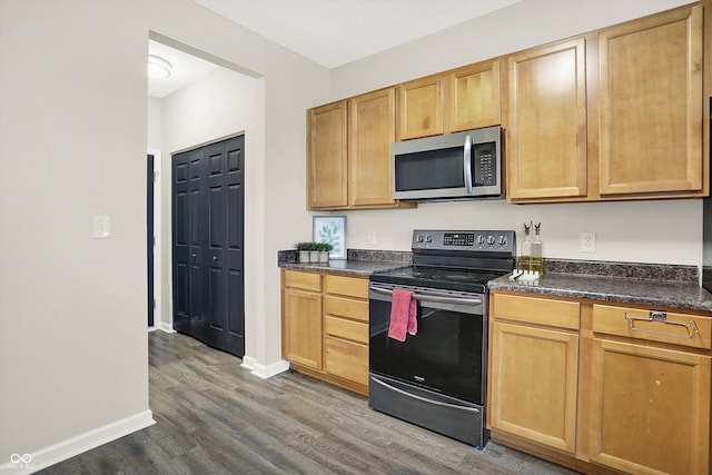 kitchen featuring stainless steel appliances, dark countertops, dark wood-type flooring, and baseboards