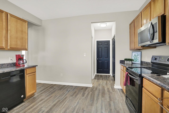 kitchen with dark countertops, dark wood-style flooring, baseboards, and black appliances