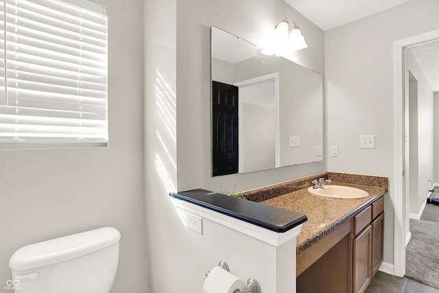 bathroom with toilet, baseboards, vanity, and tile patterned floors