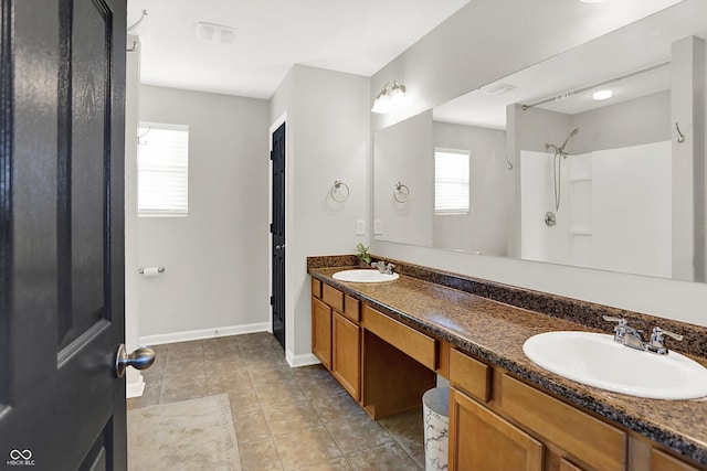 full bath with baseboards, double vanity, a sink, and tile patterned floors