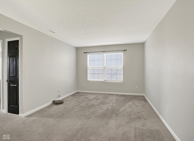 spare room featuring a textured ceiling, carpet floors, visible vents, and baseboards