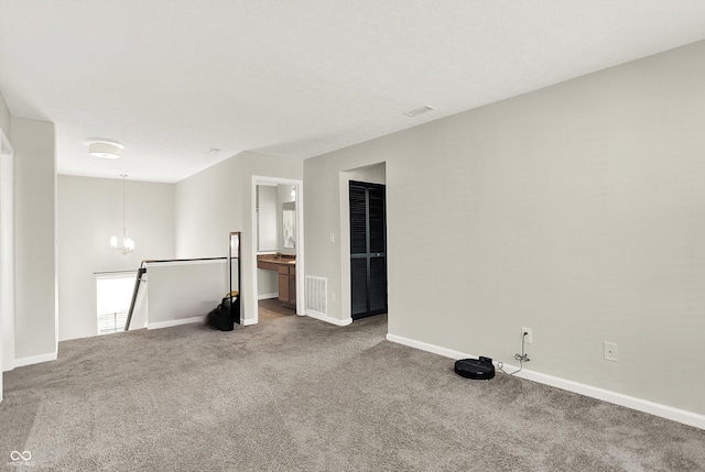 spare room featuring baseboards, carpet, visible vents, and a notable chandelier