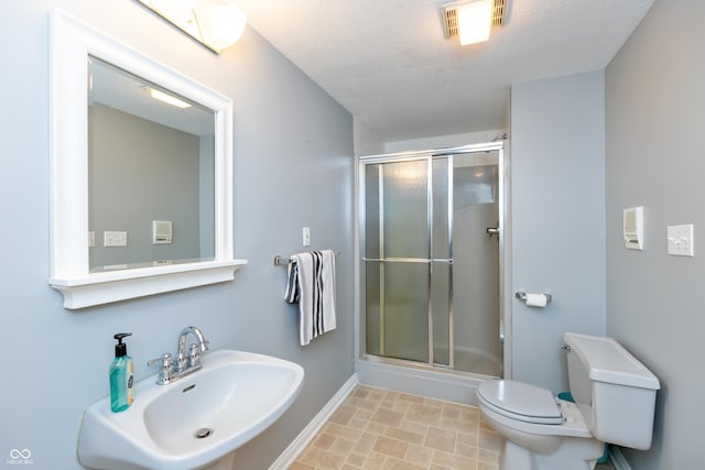 full bath featuring a shower with door, a sink, visible vents, and toilet