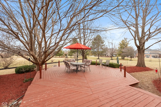 wooden terrace featuring outdoor dining space and a lawn