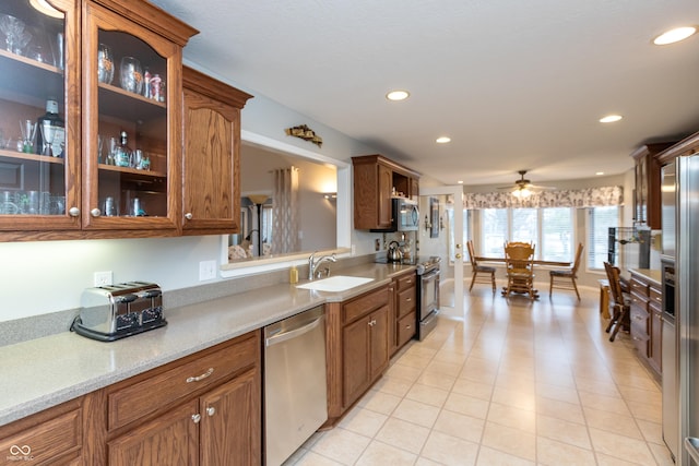 kitchen featuring appliances with stainless steel finishes, brown cabinets, light countertops, and a sink