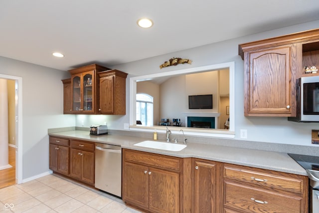 kitchen with glass insert cabinets, appliances with stainless steel finishes, light countertops, a sink, and recessed lighting