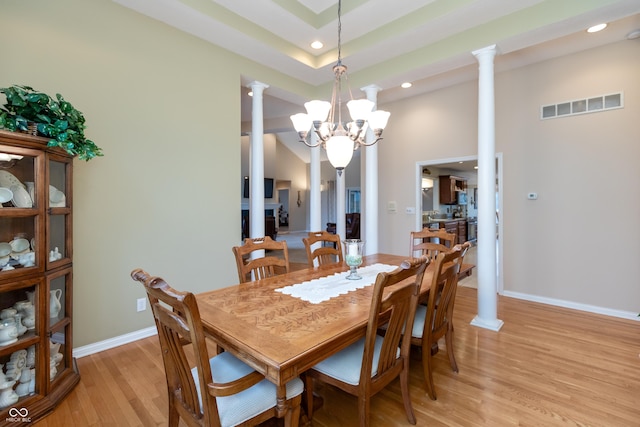 dining room featuring baseboards, light wood finished floors, visible vents, and ornate columns