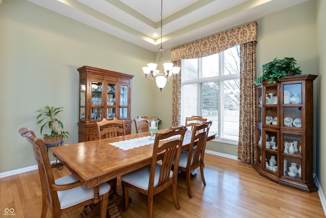 dining room with light wood-style flooring, a high ceiling, baseboards, and a wealth of natural light