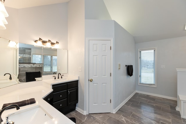 full bath with plenty of natural light, tiled shower, vaulted ceiling, and vanity