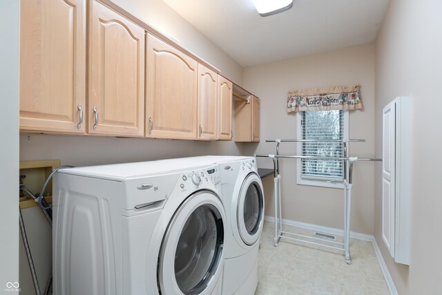 laundry room featuring washing machine and dryer, cabinet space, and baseboards