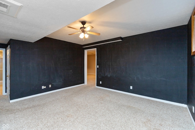 carpeted spare room featuring a textured ceiling, baseboards, and a ceiling fan