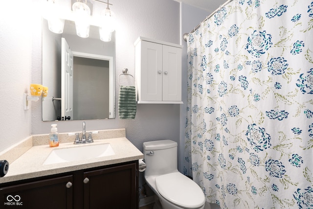 bathroom featuring a shower with curtain, a textured wall, vanity, and toilet