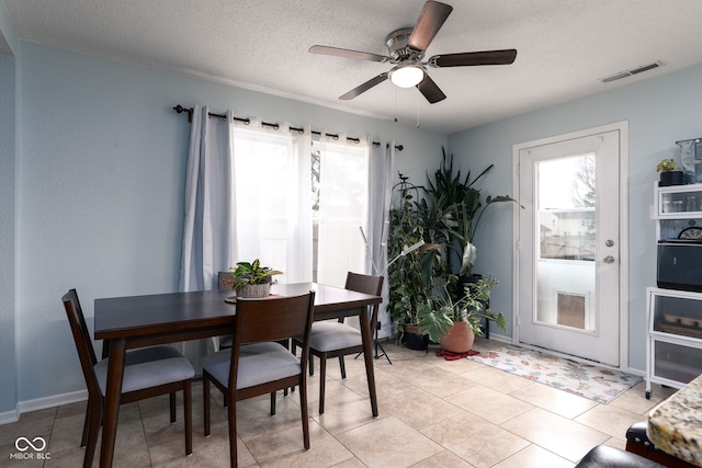 dining area with light tile patterned floors, visible vents, ceiling fan, a textured ceiling, and baseboards