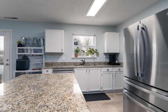 kitchen featuring white cabinetry, appliances with stainless steel finishes, light stone counters, and a sink