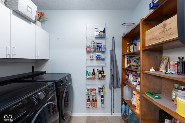 clothes washing area featuring cabinet space, baseboards, washer and clothes dryer, and a textured ceiling