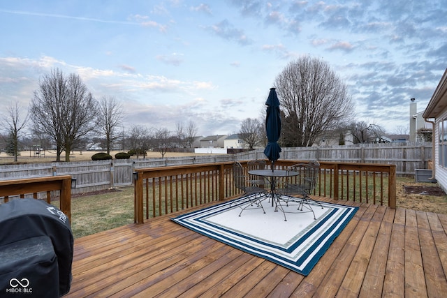 wooden deck featuring outdoor dining space, grilling area, and a fenced backyard