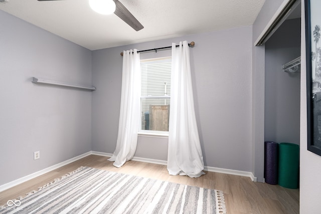 unfurnished bedroom with a ceiling fan, baseboards, and wood finished floors