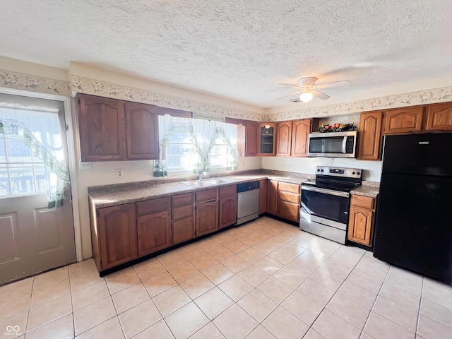 kitchen with a textured ceiling, stainless steel appliances, a sink, and light countertops