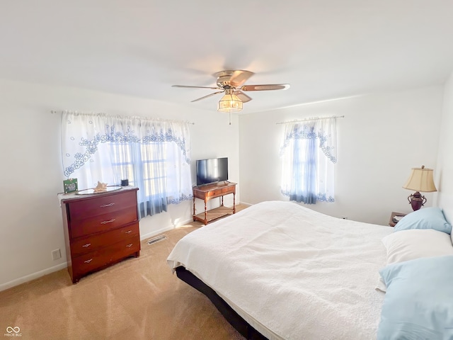 bedroom with light carpet, baseboards, visible vents, and a ceiling fan