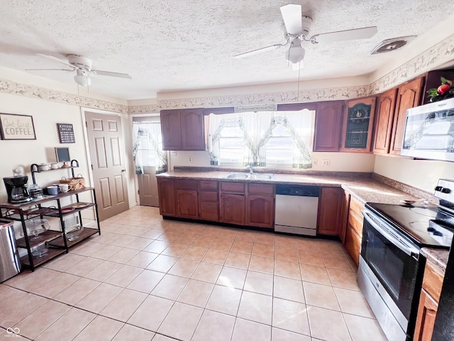 kitchen featuring stainless steel appliances, light countertops, visible vents, light tile patterned flooring, and a sink