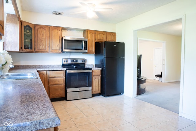 327 Maxwell Rd, Indianapolis, IN 46217 - kitchen with stainless steel appliances, brown cabinets, ceiling fan, glass insert cabinets, and a sink