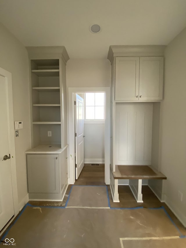 mudroom with baseboards, concrete flooring, and built in features