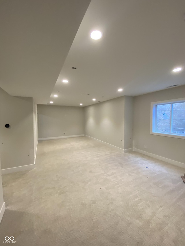 basement featuring light carpet, baseboards, and recessed lighting