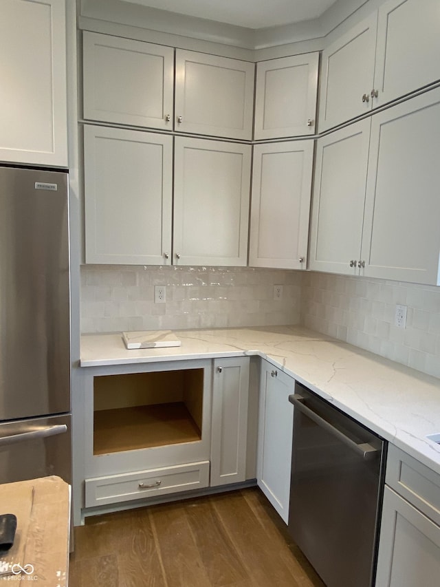 kitchen with light stone counters, decorative backsplash, stainless steel appliances, and dark wood finished floors