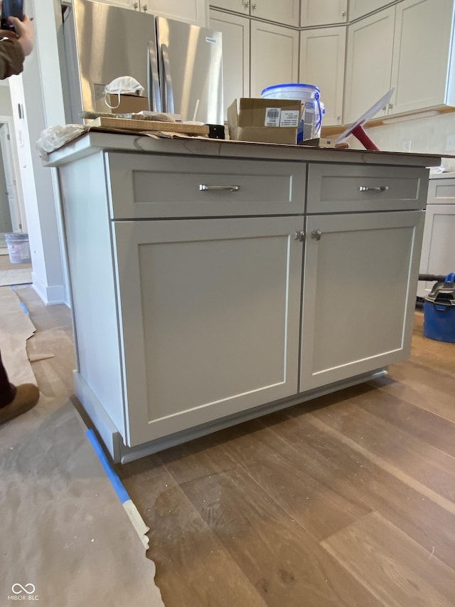 kitchen featuring freestanding refrigerator, dark countertops, gray cabinetry, and wood finished floors