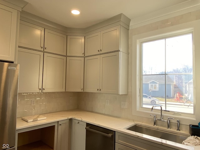 kitchen with light stone counters, gray cabinetry, decorative backsplash, appliances with stainless steel finishes, and a sink